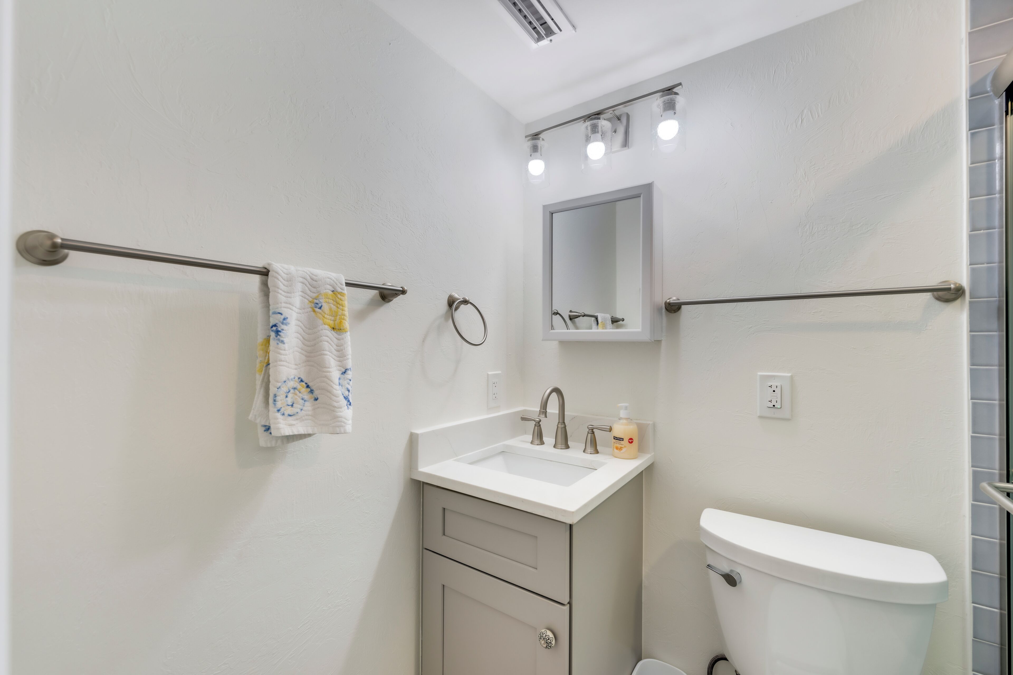 A bathroom with a white sink, a toilet, and a towel rack.