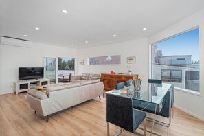 Relax in this stylish living space with a large flat-screen TV, comfortable sofa, and dining table.