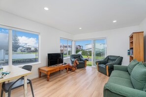Relax in this peaceful living room with a large window offering views of the surrounding neighborhood, a comfortable sofa, and two armchairs.