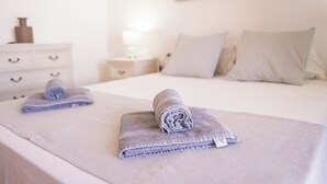 A neatly made bed with two rolled towels and a white nightstand with a lamp. - Villa Luisa: Relax with ocean view and swimming pool (Los Abrigos)