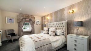 Une chambre à coucher avec un grand lit, une chaise, une table de chevet et une lampe.