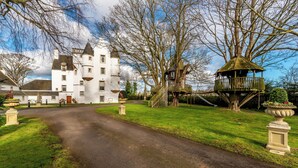Un château avec une allée sinueuse menant à un grand bâtiment blanc doté de nombreuses tours.