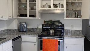 A kitchen with white cabinets, a stove, and a checkered floor.