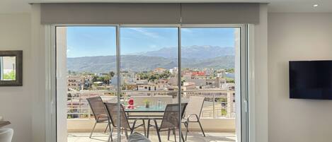 Un moderno salón con un amplio ventanal corredera que da a un balcón con vista a la ciudad.