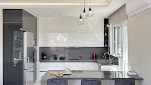 Una cocina moderna con una isla central, electrodomésticos de acero inoxidable e iluminación colgante.
