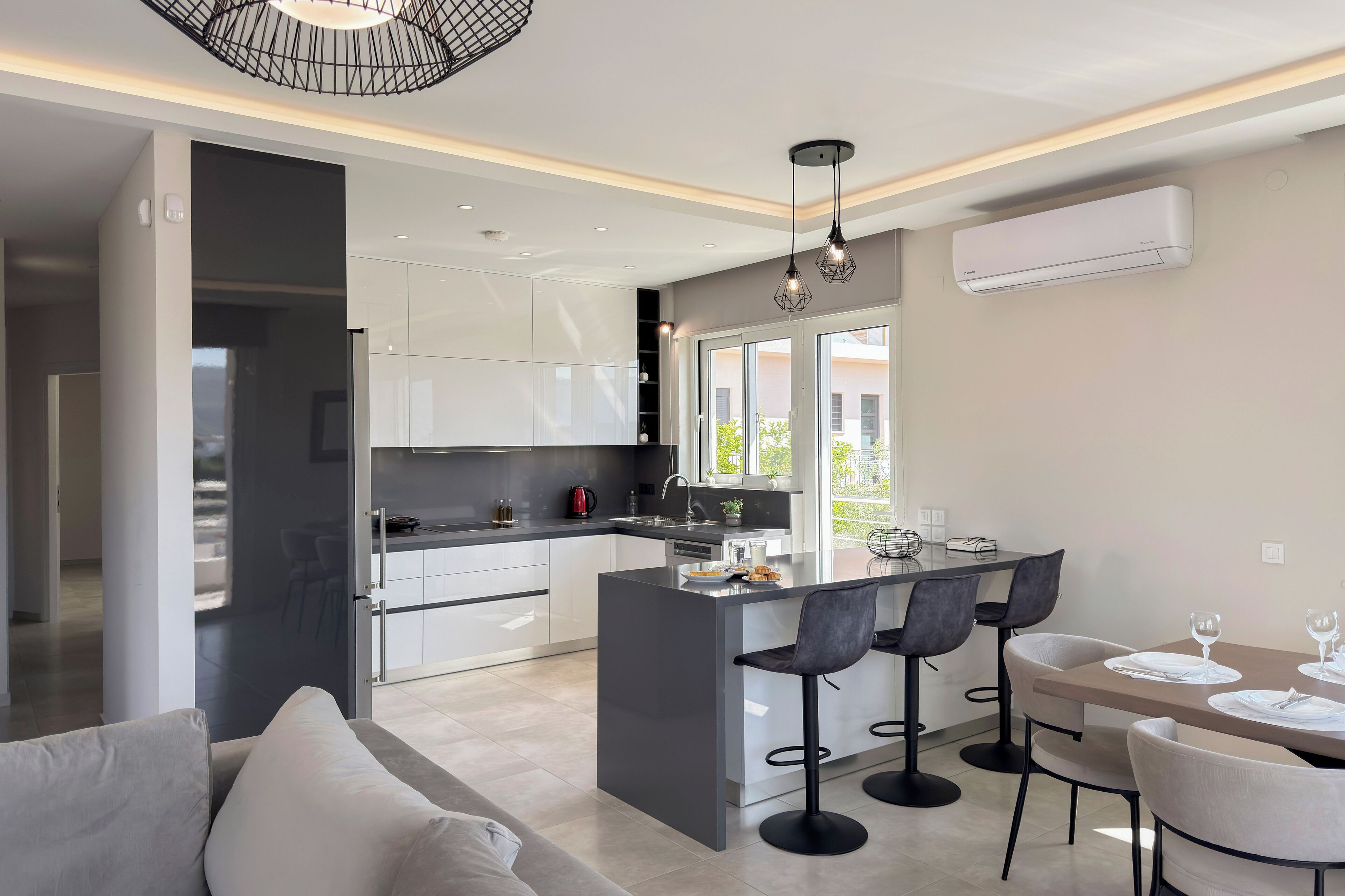 A modern kitchen with a central island, bar stools, and a dining area with a table and chairs.