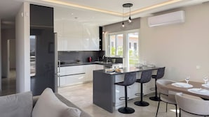 Una cocina moderna con una isla central, taburetes de bar y una zona de comedor con mesa y sillas.