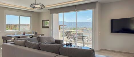 Ein modernes Wohnzimmer mit einer großen Couch, einem Essbereich und einem Balkon mit Blick auf die Stadt.
