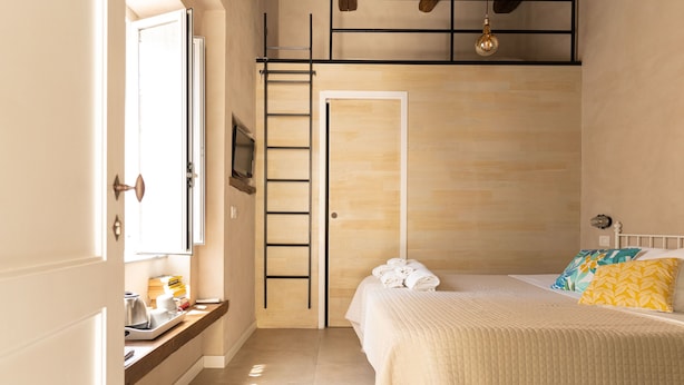Une chambre à coucher avec un lit, une fenêtre, un bureau avec une bouilloire et une échelle.