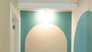 Un couloir avec une porte donnant sur une pièce, un mur d’accent de couleur turquoise et un plafond blanc.