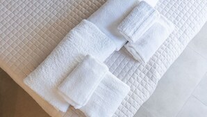 Une serviette blanche, soigneusement pliée, est posée sur un tapis de bain beige à motifs matelassés.