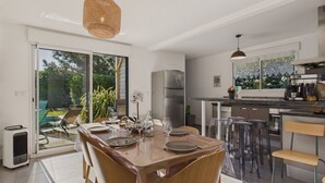 Una cocina moderna con una isla grande, electrodomésticos de acero inoxidable y un comedor con mesa y sillas de vidrio.
