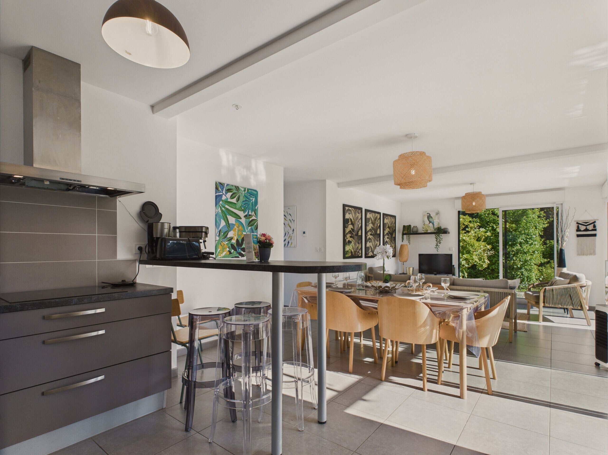 A modern kitchen with a dining area, featuring a large island, bar stools, and a view of the outdoors.