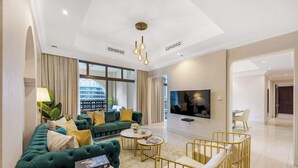 Una sala de estar moderna con un sofá verde, detalles dorados, un televisor de pantalla plana y un ventanal grande.