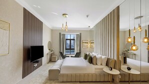 Habitación de hotel moderna con una cama grande, televisión, zona de estar y vistas a la ciudad.