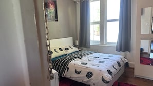 A bedroom with a bed, a window with curtains, a mirror, and a door. - 3b-10min City Airport, Parking, No Parties Allowed (London)