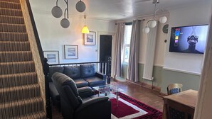 A living room with a sofa, a glass coffee table, a red rug, a TV, and a staircase. - 3b-10min City Airport, Parking, No Parties Allowed (London)
