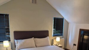 A bedroom with a large bed, two bedside tables with lamps, wooden flooring, and a sloped ceiling with a vent. - 3b-10min City Airport, Parking, No Parties Allowed (London)