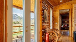 Een houten blokhut interieur met uitzicht op een bergachtig landschap door grote ramen.