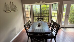 A dining room with a large table, chairs, and a chandelier.