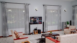 A living room with a flat-screen TV mounted on the wall, two armchairs, a coffee table, and a small side table.