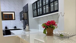A modern kitchen with marble countertops, black cabinets, and a small window.