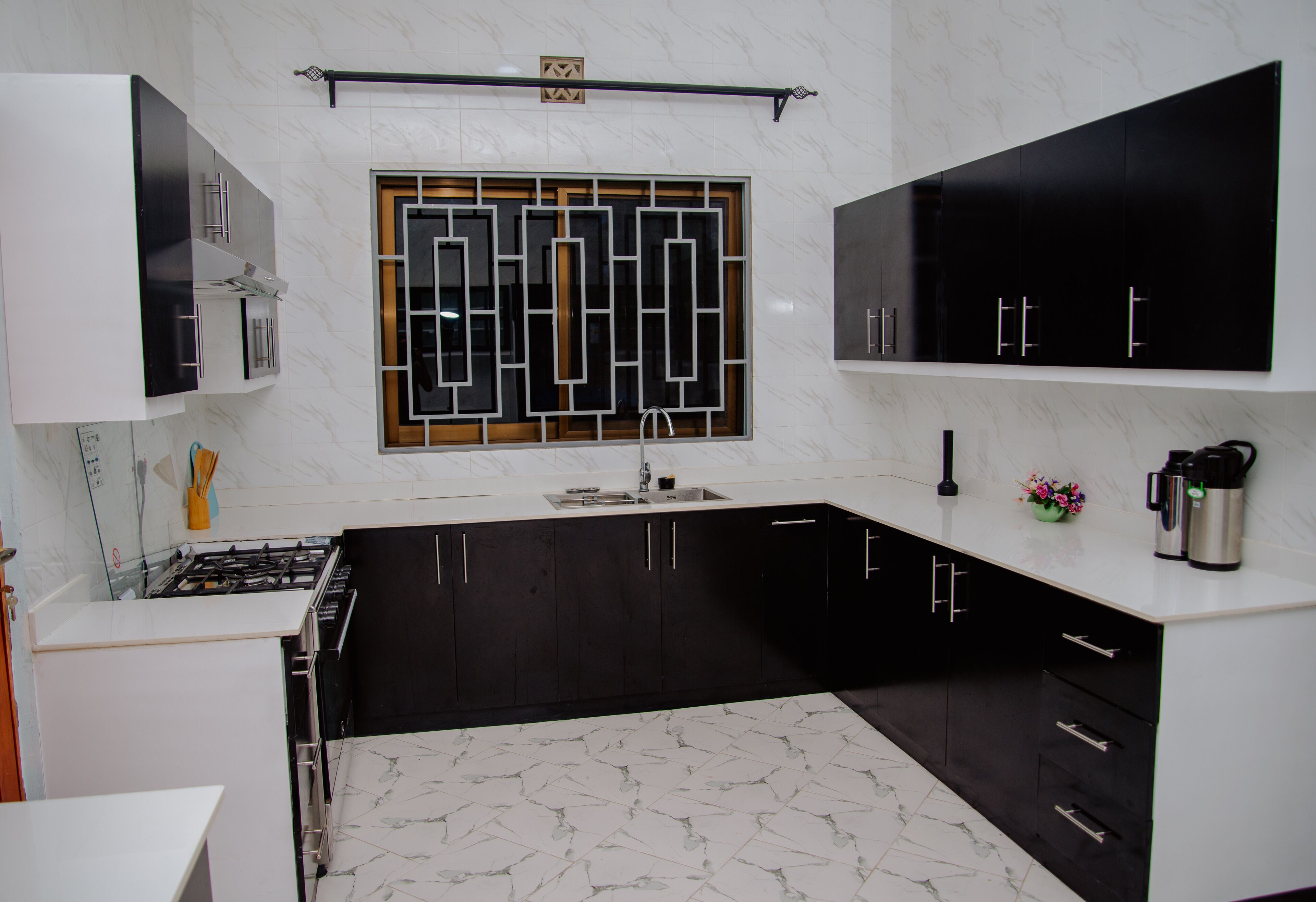 A modern kitchen with black and white cabinetry, a stainless steel sink, and a marble backsplash.