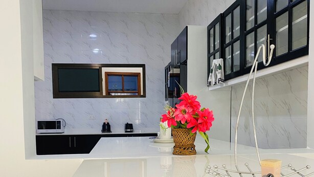A modern kitchen with a marble backsplash, black cabinets, a built-in microwave, and a decorative vase with flowers.