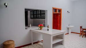 A modern bathroom with a white vanity, a mirror, a red door, and a white sink.