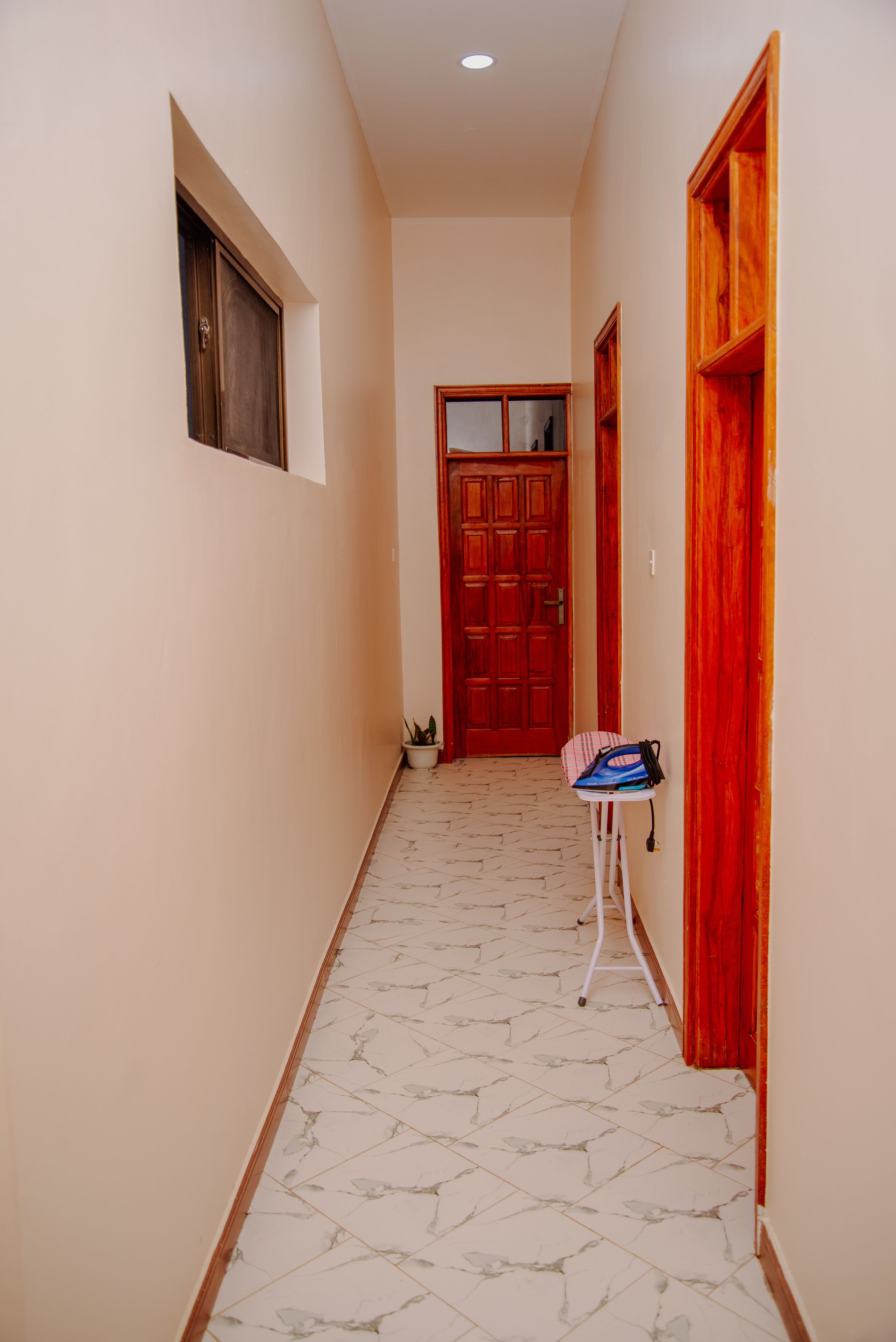 A hallway with a marble floor, a wooden door, and a small table with a bag on it.