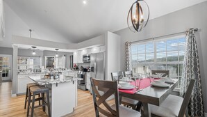 A modern kitchen with white cabinets, a central island, and a dining area with a red tablecloth. - 3 King Suites near Silver Dollar City & the Strip (Branson)