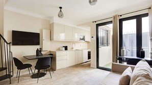 Apartament modern amb cuina, zona de dinar i saló amb sofà i un balcó.