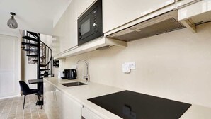 Una cuina moderna amb fogó d'inducció negre, forn de microones integrat i un rentaplat amb acer inoxidable.