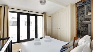 Habitació d'hotel amb un llit gran, un bany amb un rentapeus de marbre i vistes per la finestra.