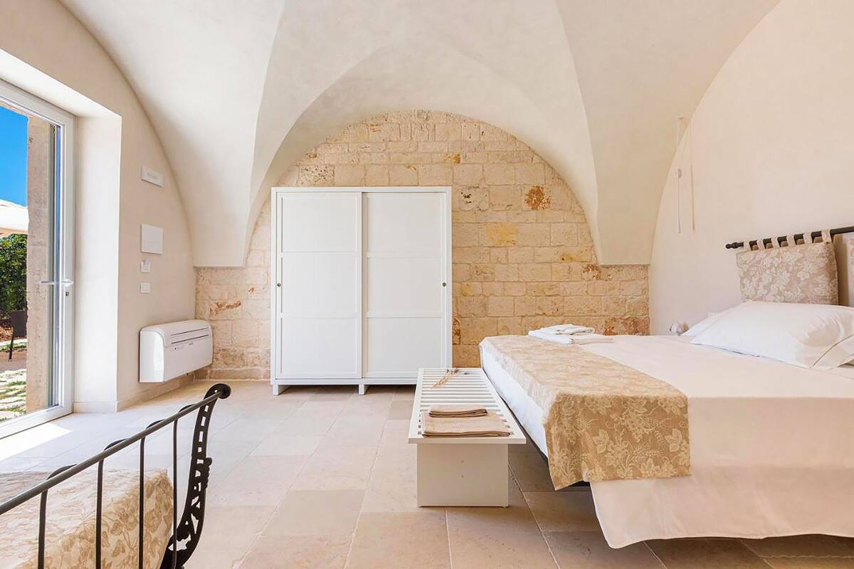 Un dormitorio con cama, armario, banco y vistas al exterior.