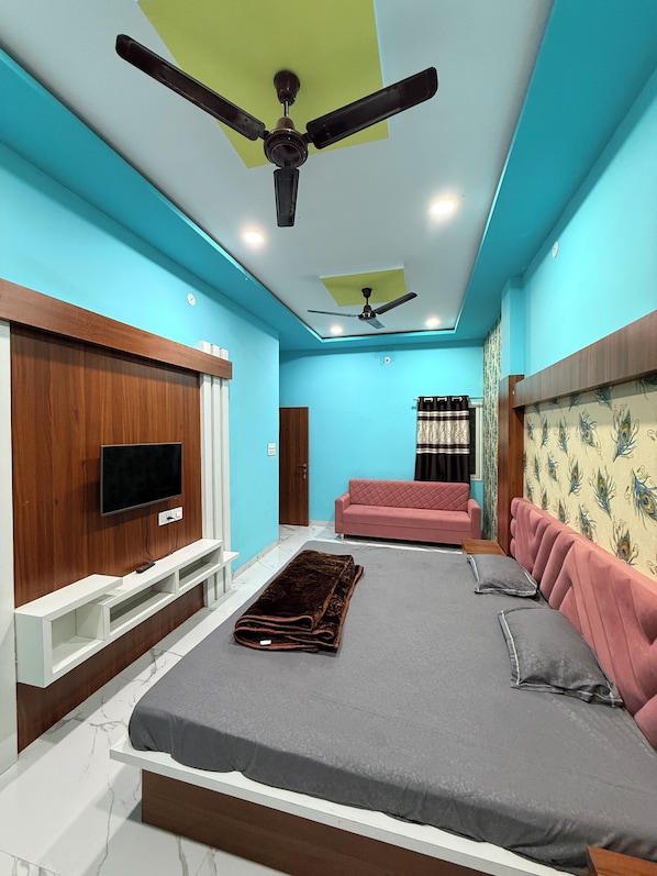 A modern bedroom with a bed, a TV, a ceiling fan, and a window with curtains.