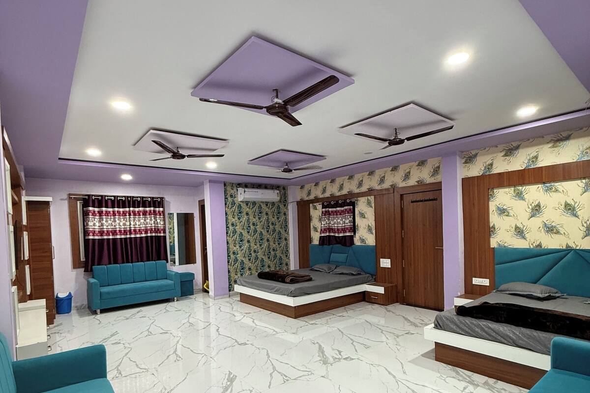 Un vaste espace de vie comprenant un grand canapé, un lit et un ventilateur de plafond.