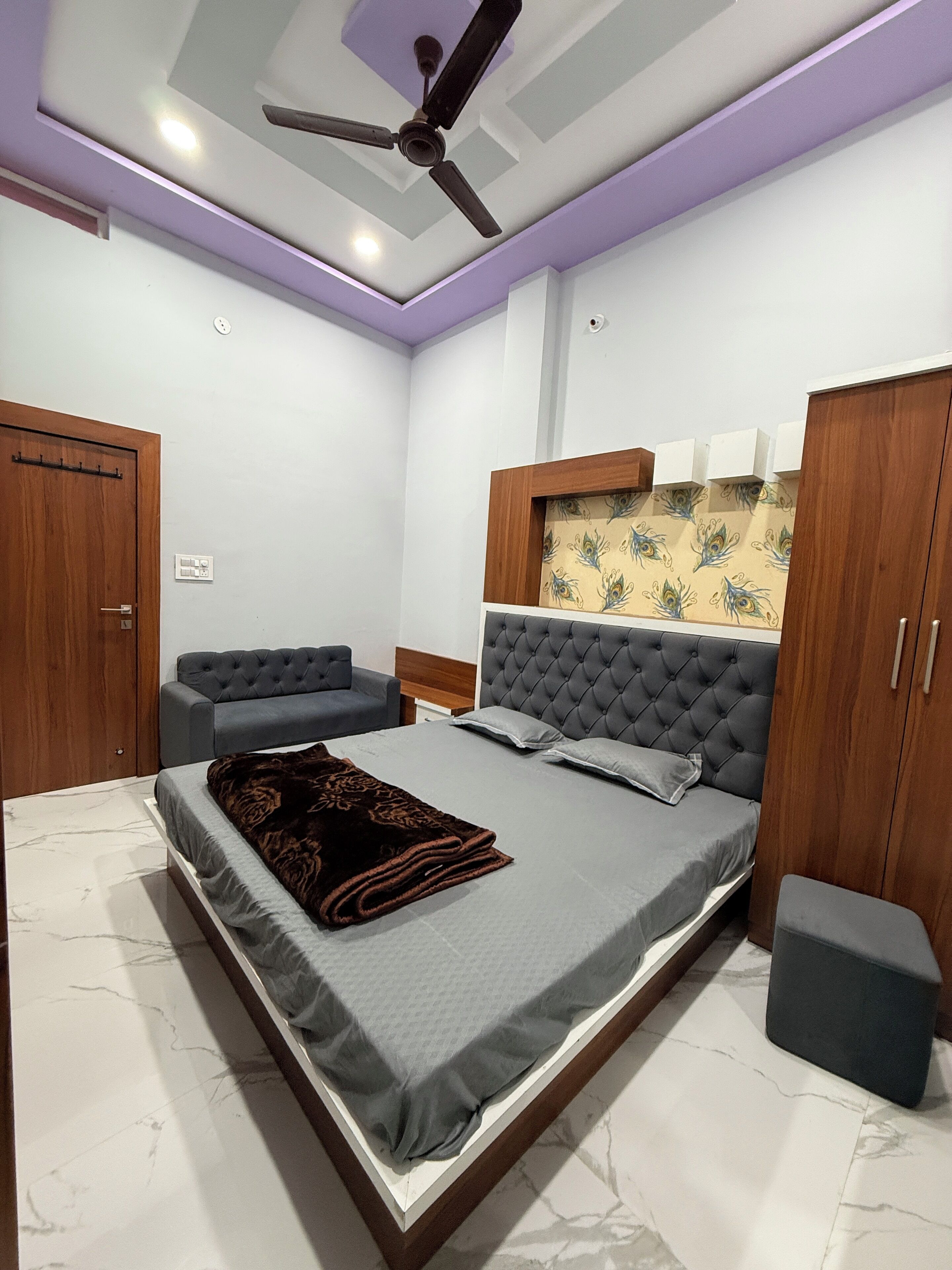 Ein Schlafzimmer mit einem Bett, einem Deckenventilator, einem Kleiderschrank und einer Sitzecke.