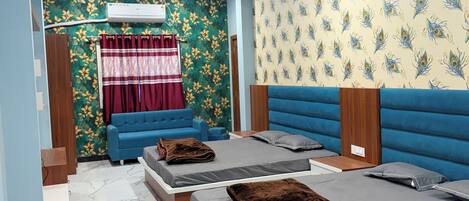 A bedroom with two beds, a blue sofa, a red curtain, and a ceiling fan.