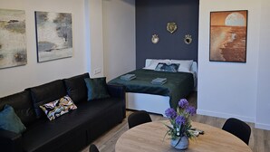 A modern, compact room with a bed, a sofa, a dining table, and a chandelier. - Inspiracion Valencia (València)