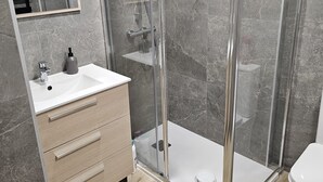 A modern bathroom with a glass-enclosed shower, a white sink, and a wooden vanity. - Inspiracion Valencia (València)