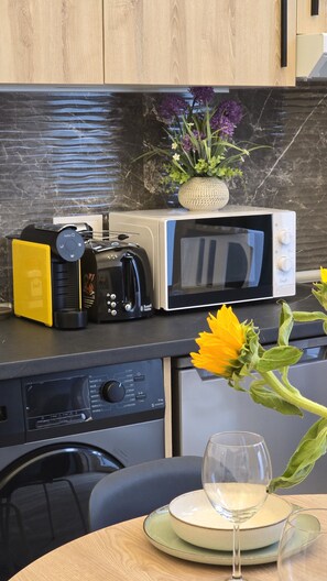 A kitchen with a microwave, coffee maker, and a vase with flowers on the counter. - Inspiracion Valencia (València)
