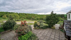 Un jardin doté d’une zone pavée, d’une éolienne et offrant une vue sur un paysage verdoyant.