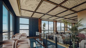 Un salón moderno con una barrera de vidrio, asientos cómodos y vistas a la ciudad.