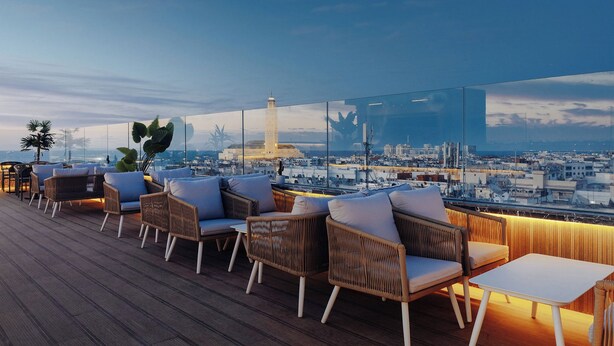 Terraza en la azotea con mobiliario de mimbre y vista a la ciudad.