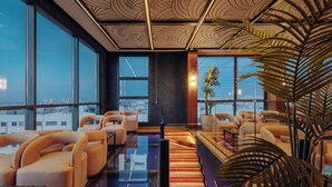 Un salón moderno con ventanas amplias, asientos cómodos y un techo decorativo.