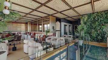 A spacious lobby with a high ceiling, modern seating, and a glass railing overlooking a pool.