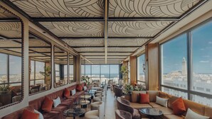 Un salón moderno con sofás de cuero, mesas de mármol y ventanas amplias con vistas a la ciudad.