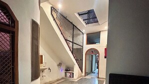 Un amplio pasillo con piso de mármol, una escalera con barandal metálico y vista a otra habitación.