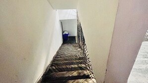 A narrow stairway with a patterned carpet leading to a room with a white door and a blue object on the floor. - AGRAWAL INN Guest House  (Mathura)